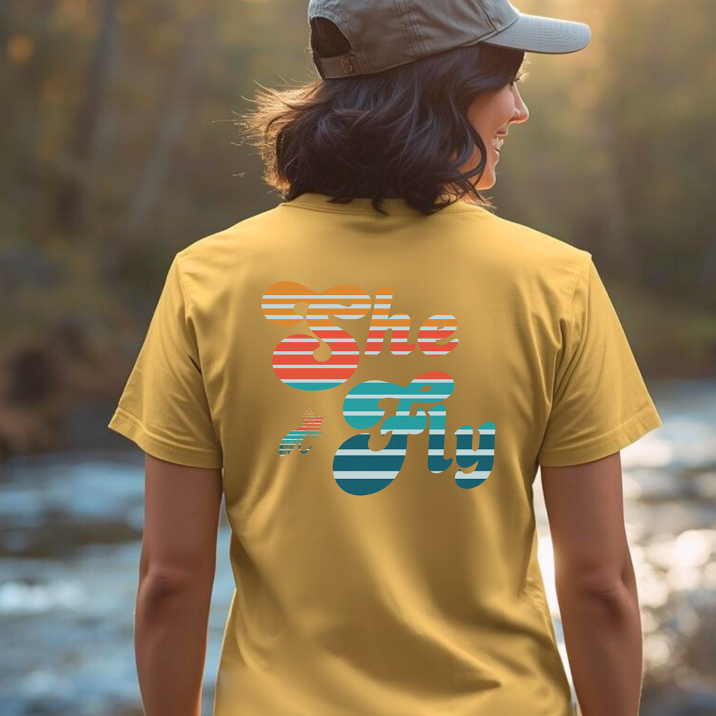 Lifestyle photo of a person wearing the retro “She Fly” fly fishing tee outdoors.