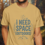 Person wearing a beige t-shirt with 'I Need Space Outdoors' text and graphics.