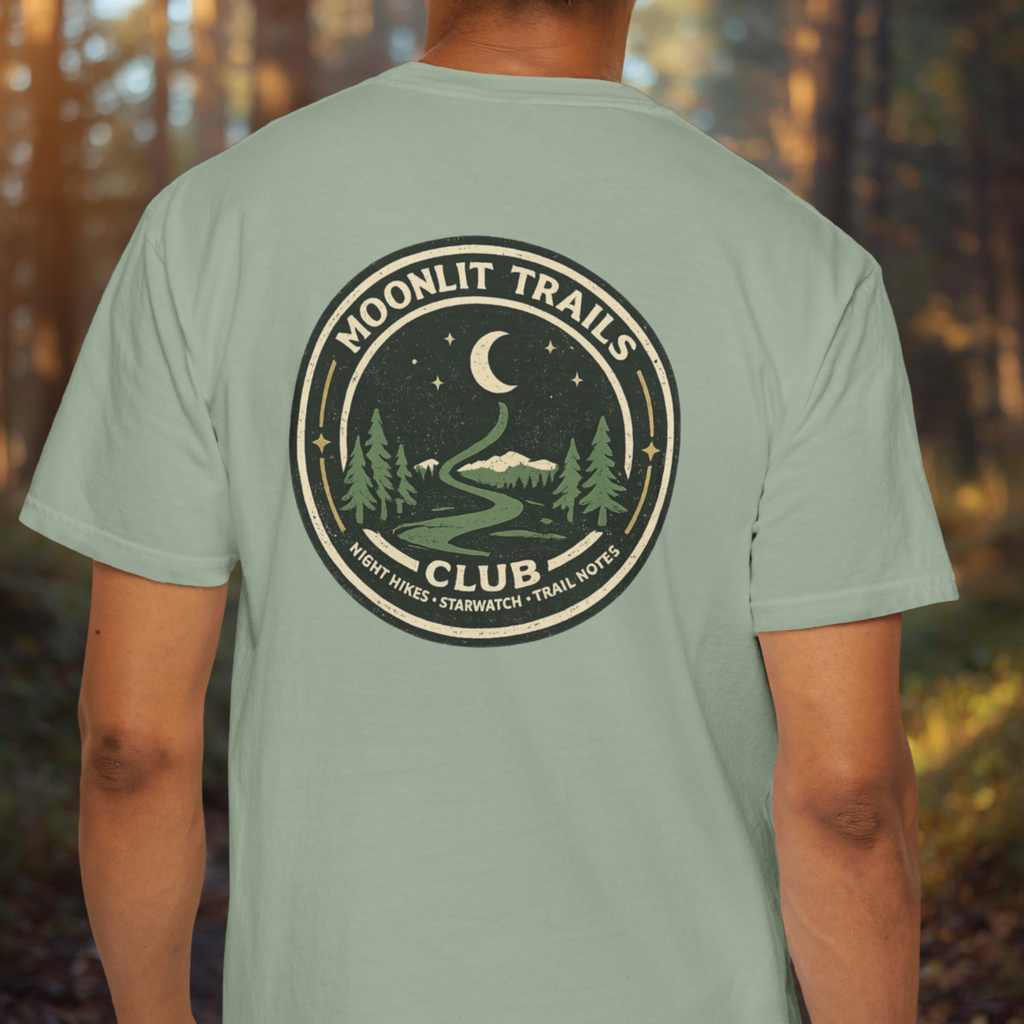 Person wearing a green t-shirt with 'Moonlit Trails Club' design in a forest setting