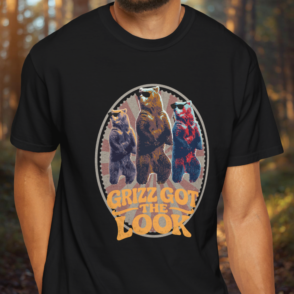 Black t-shirt with bear graphic and 'Grizz Got the Look' text worn by a person in a forest setting.