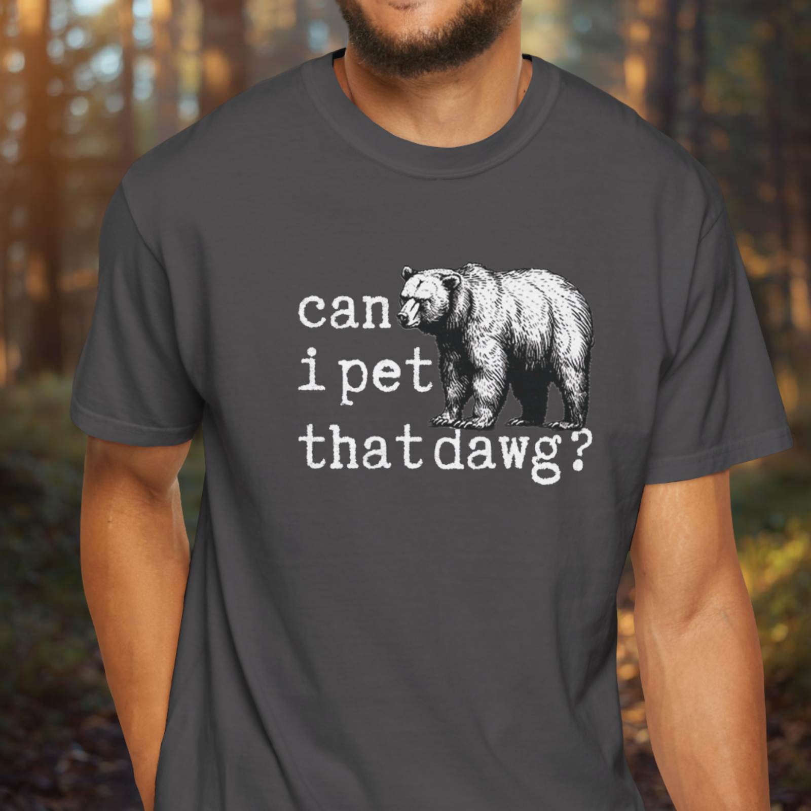 Person wearing a dark gray t-shirt with a bear graphic and text in a forest setting