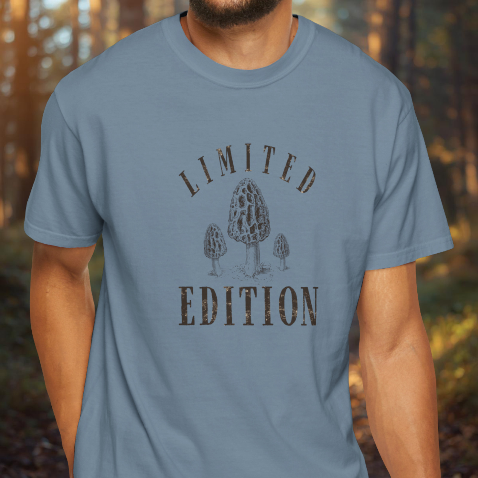 Person wearing an ice blue t-shirt with 'Limited Edition' and mushroom design in a forest setting