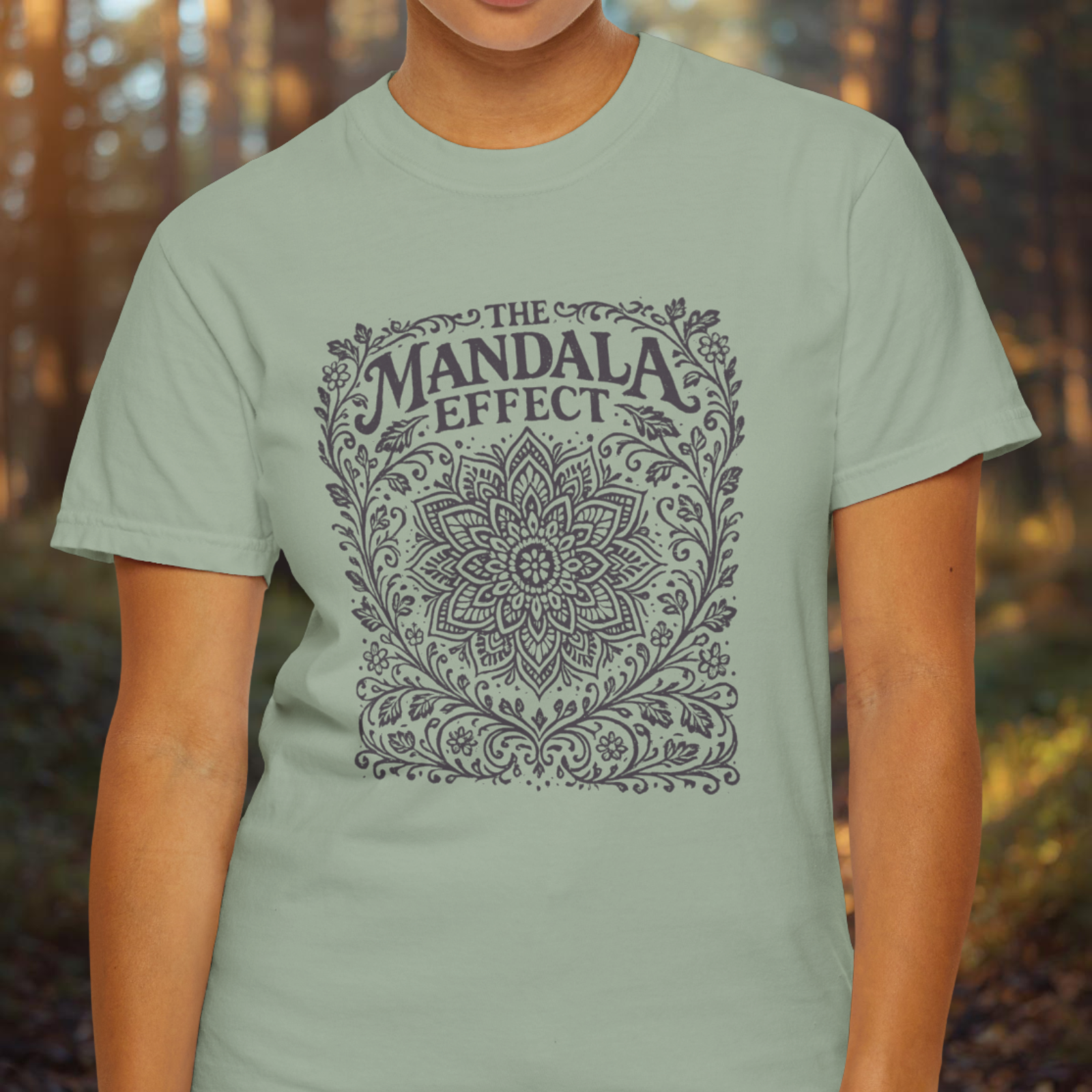 Person wearing a light green t-shirt with 'The Mandala Effect' design.