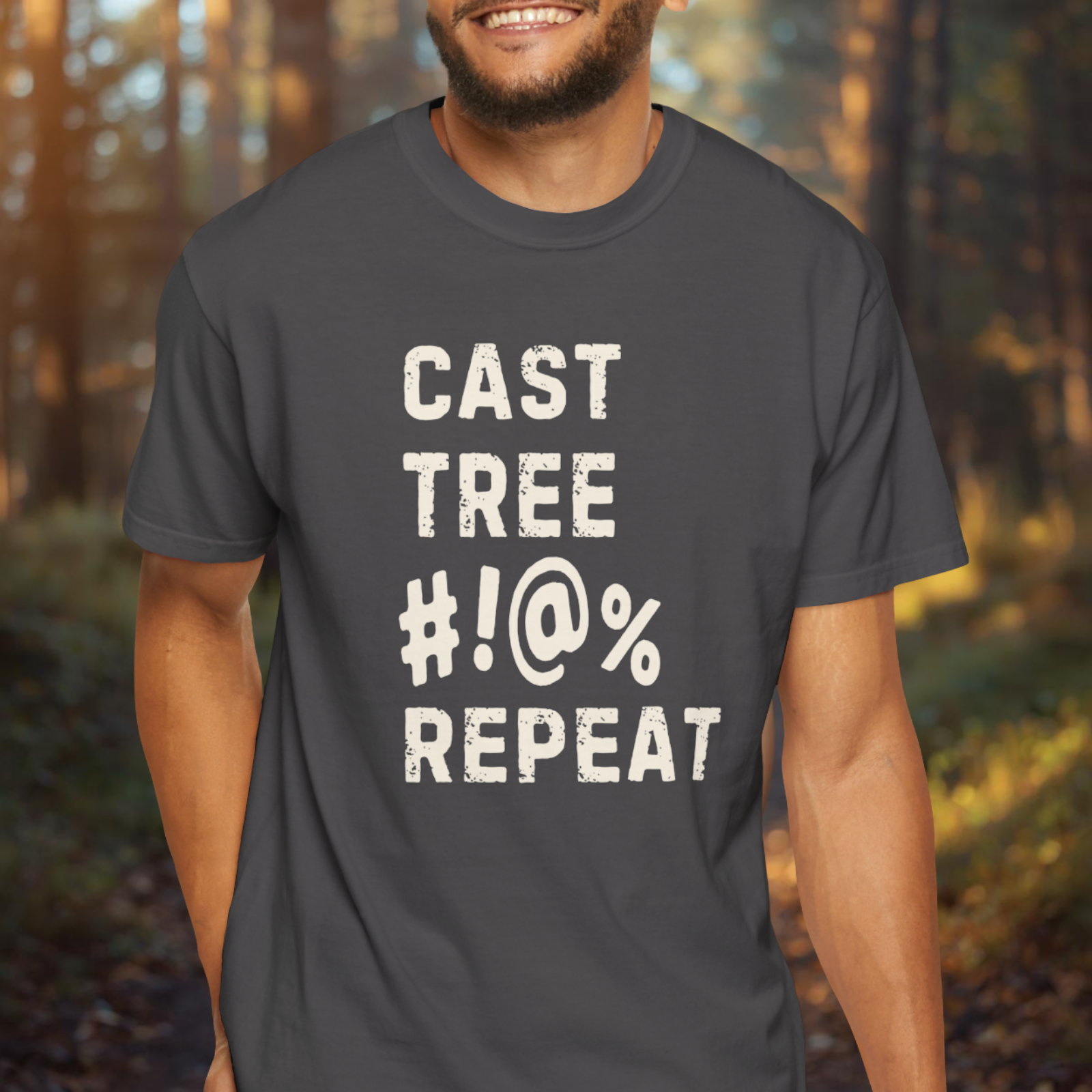 Person wearing a dark t-shirt with Cast Tree #!@% Repeat text in a forest setting