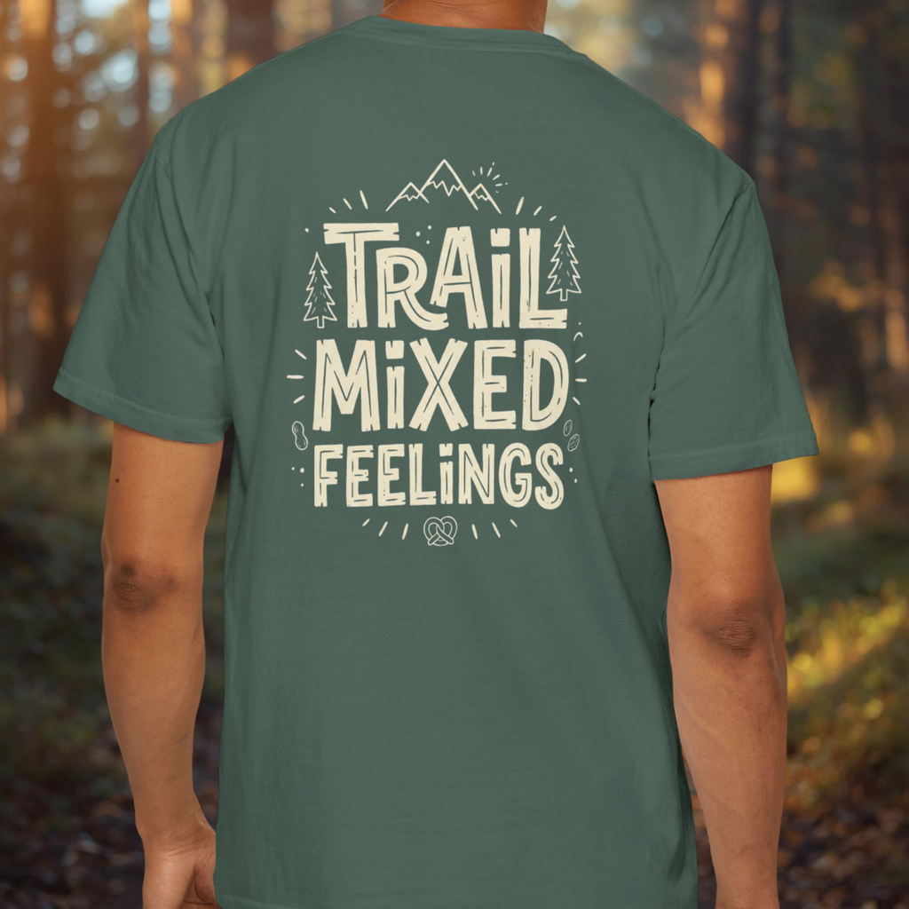 Person wearing a blue spruce t-shirt with 'Trail Mixed Feelings' text in a forest setting