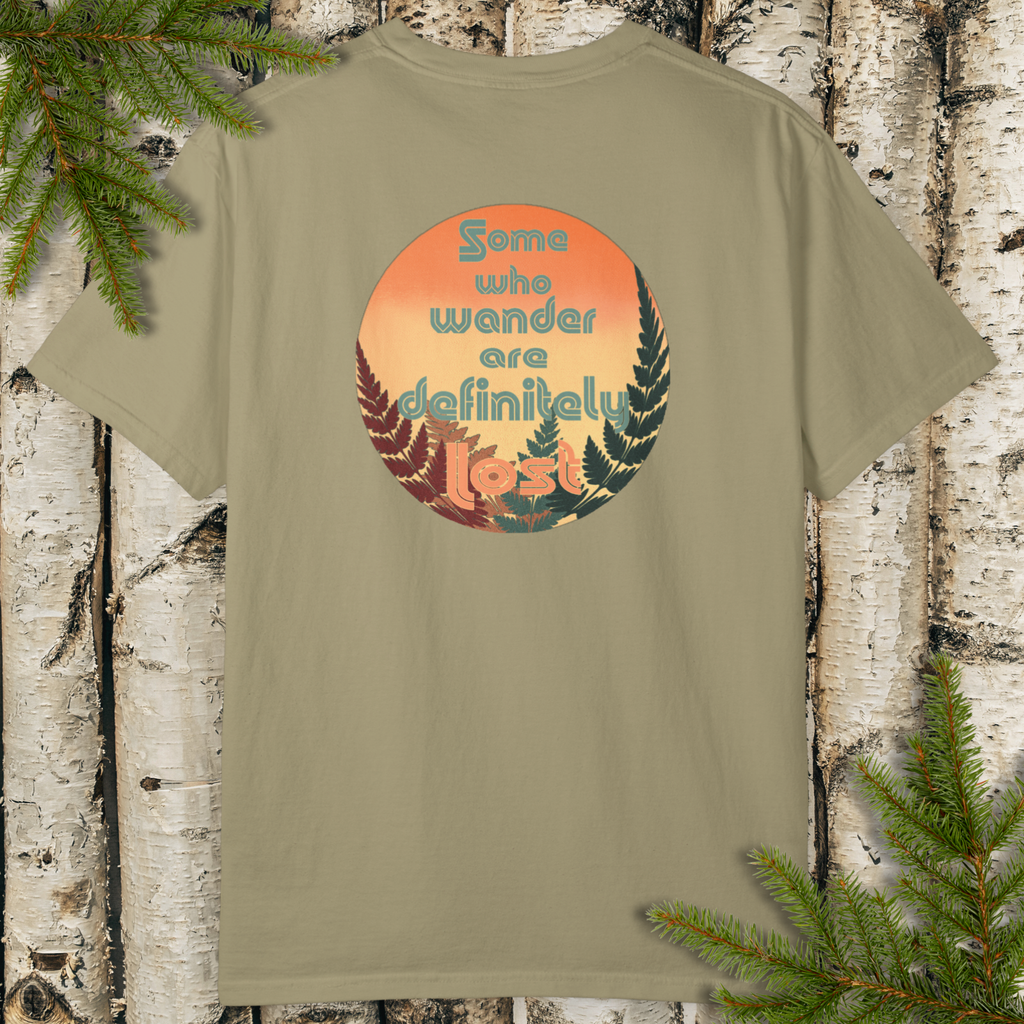 Khaki green garment-dyed t-shirt with a round sunset badge, fern silhouettes, and “Some who wander are definitely lost" graphic.