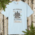 We Forage at Dawn morel mushroom graphic t-shirt flat lay on wood background.