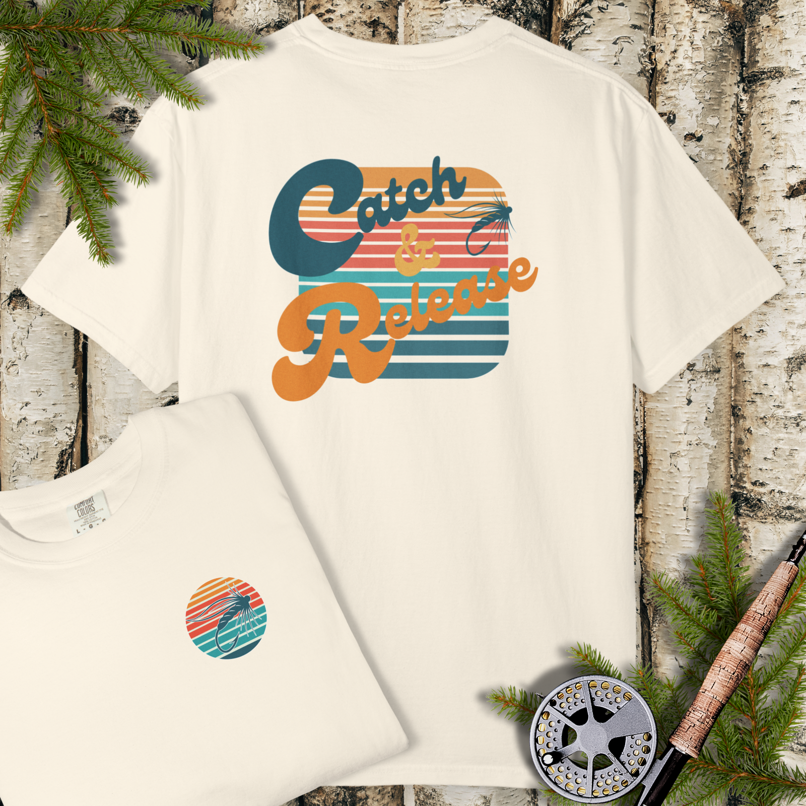 Flat lay of light/cream t-shirt with retro “Catch & Release” sunset fly fishing graphic and small left-chest badge detail.