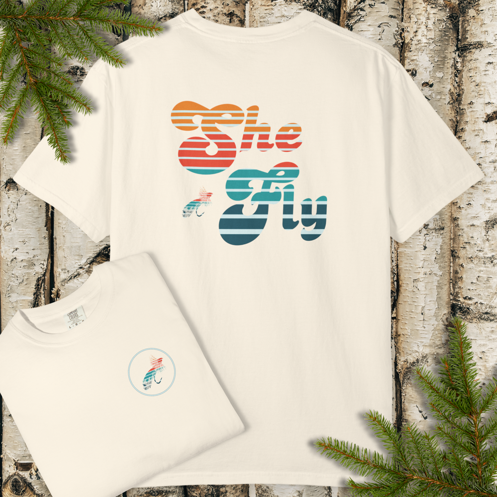 Ivory garment-dyed t-shirt with a large retro striped “She Fly” fly fishing graphic on the back.