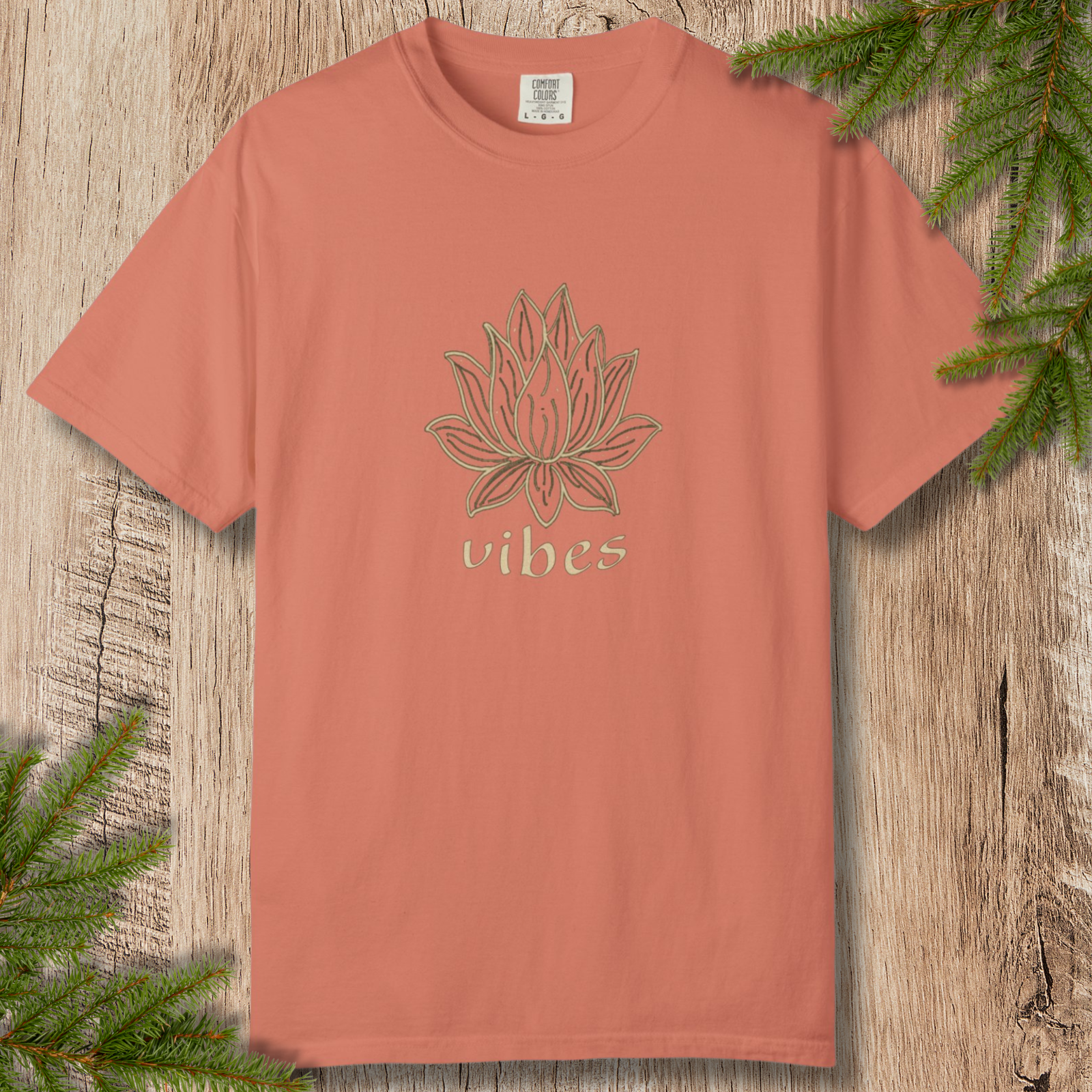 Terracotta t-shirt with line-drawn lotus flower and “vibes” text on a wooden background