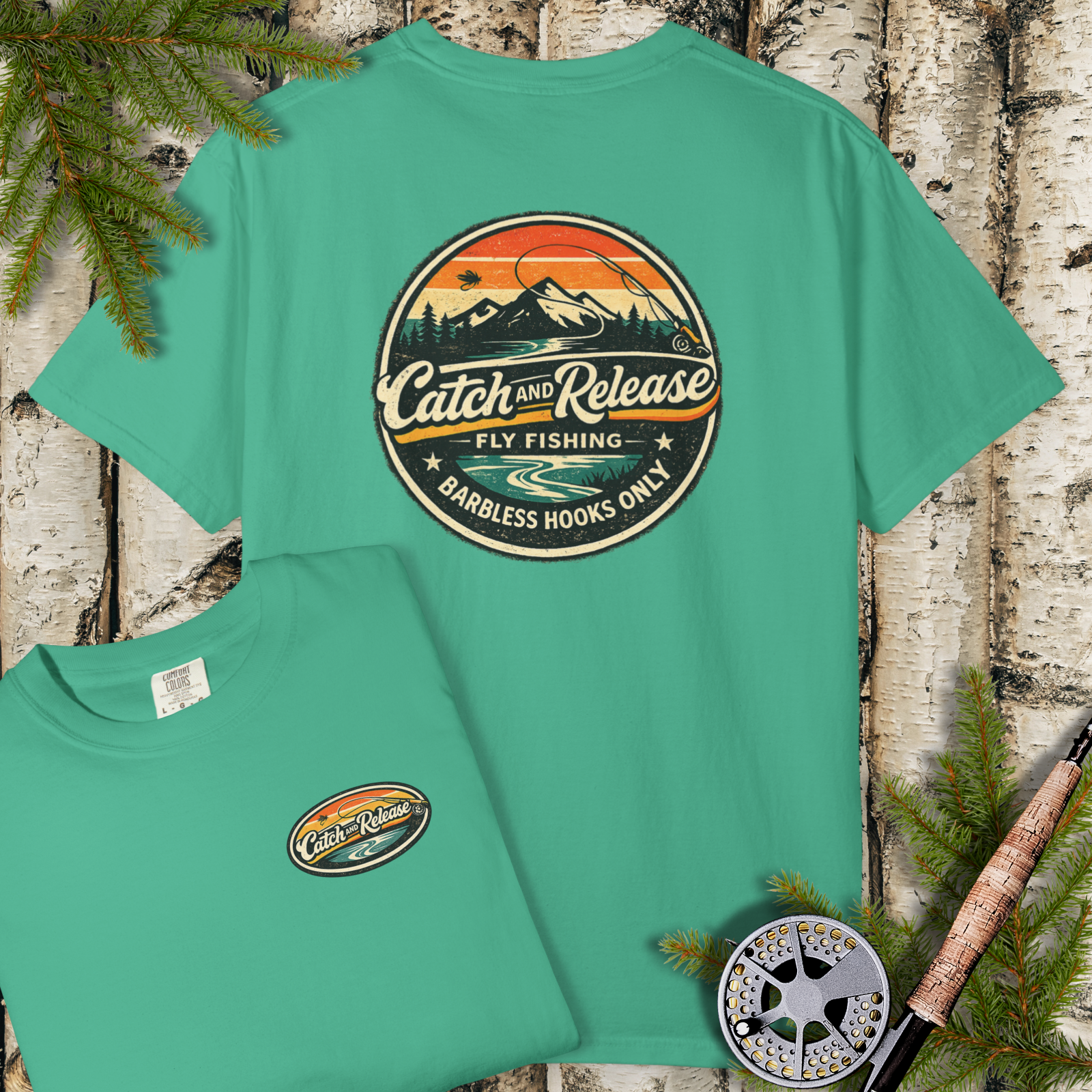 Flat lay of green garment-dyed t-shirt with large “Catch & Release” fly fishing badge on the back and small chest emblem.