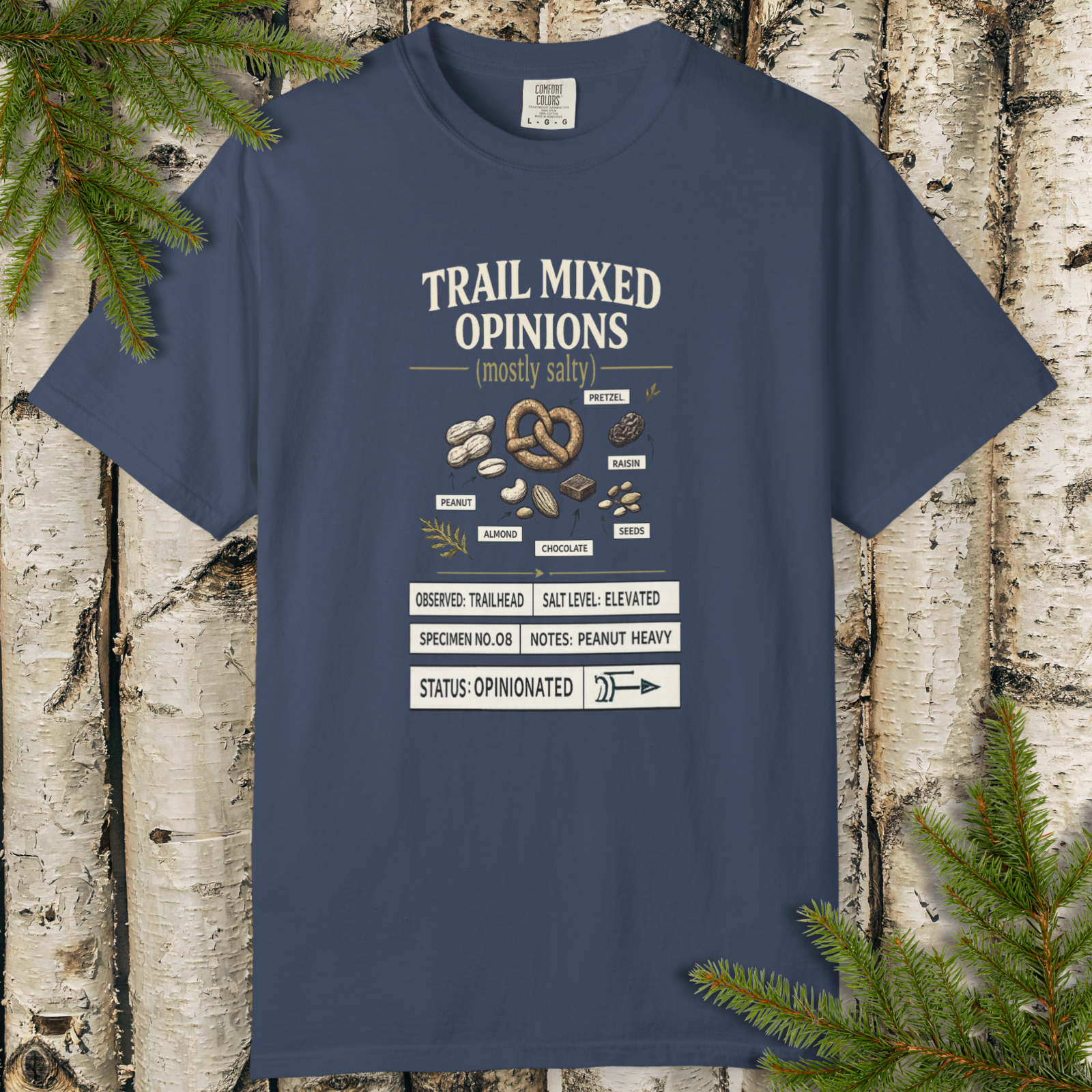 Trail Mixed Opinions field guide hiking snack graphic t-shirt flat lay on wood background.