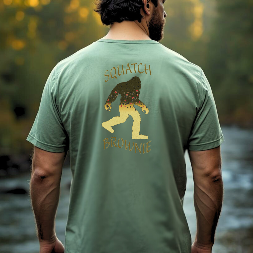 Person wearing Squatch Brownie brown trout Bigfoot tee outdoors
