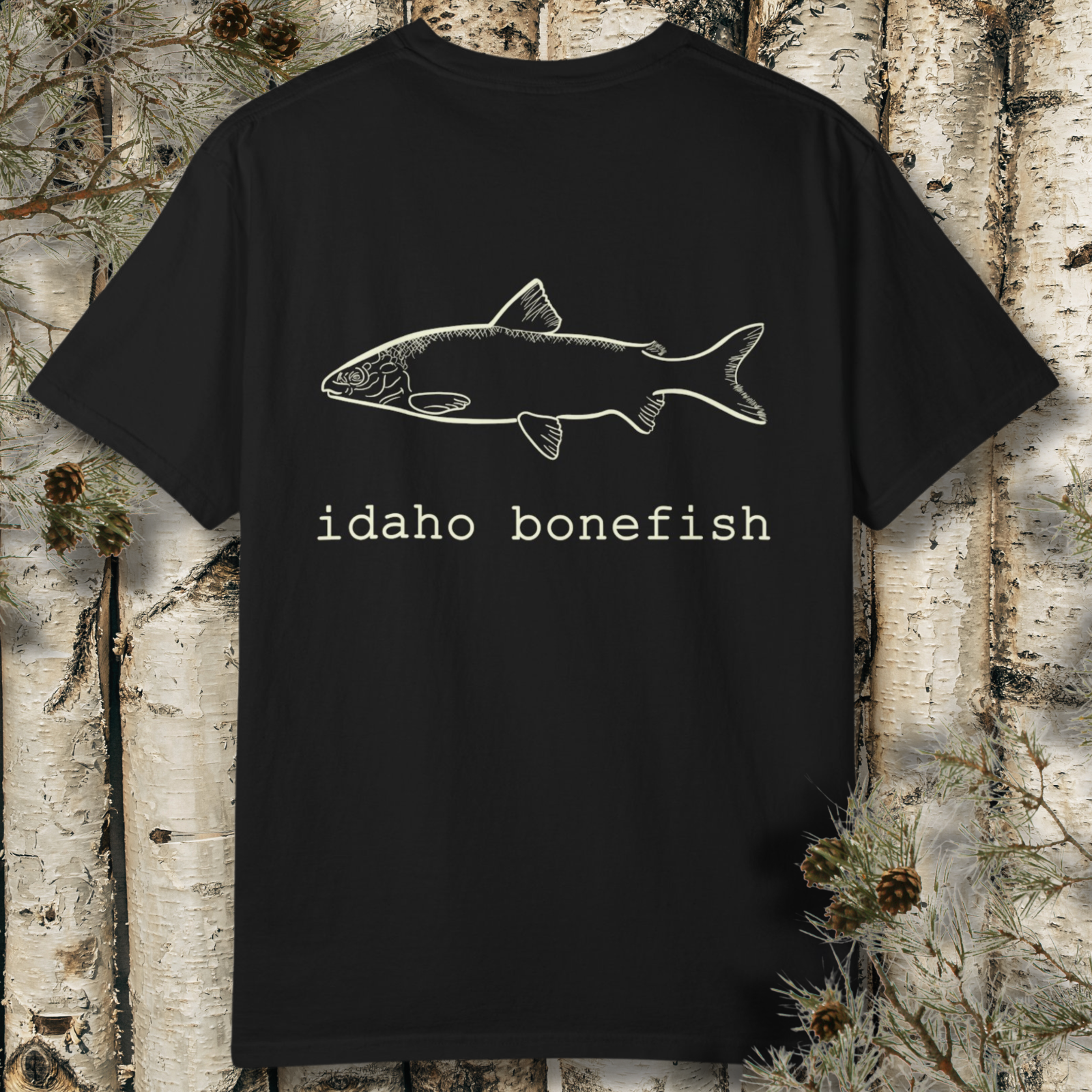 Flat lay of black t-shirt with a hand drawn sketch of a river whitefish and "Idaho Bonefish" in old typewriter font on the back.