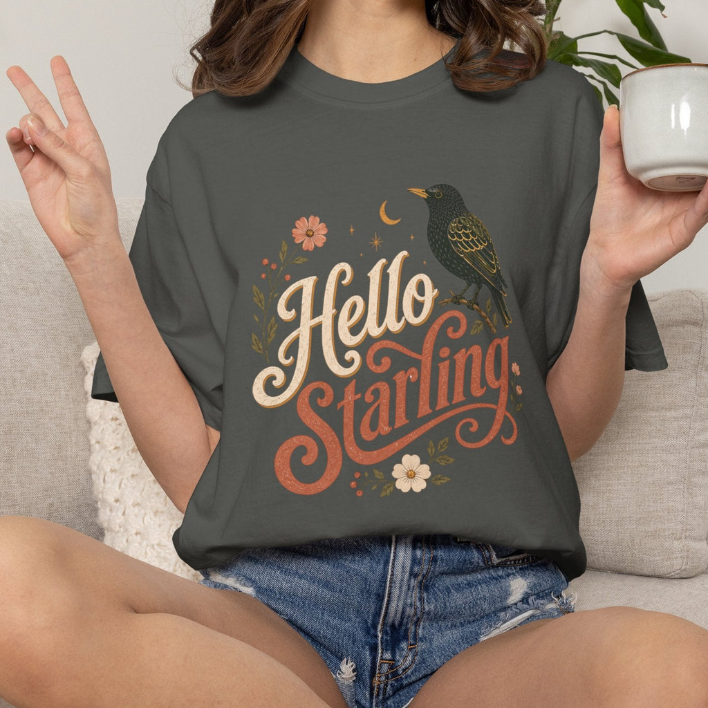 Person wearing a 'Hello Starling' t-shirt holding a mug in a casual setting.