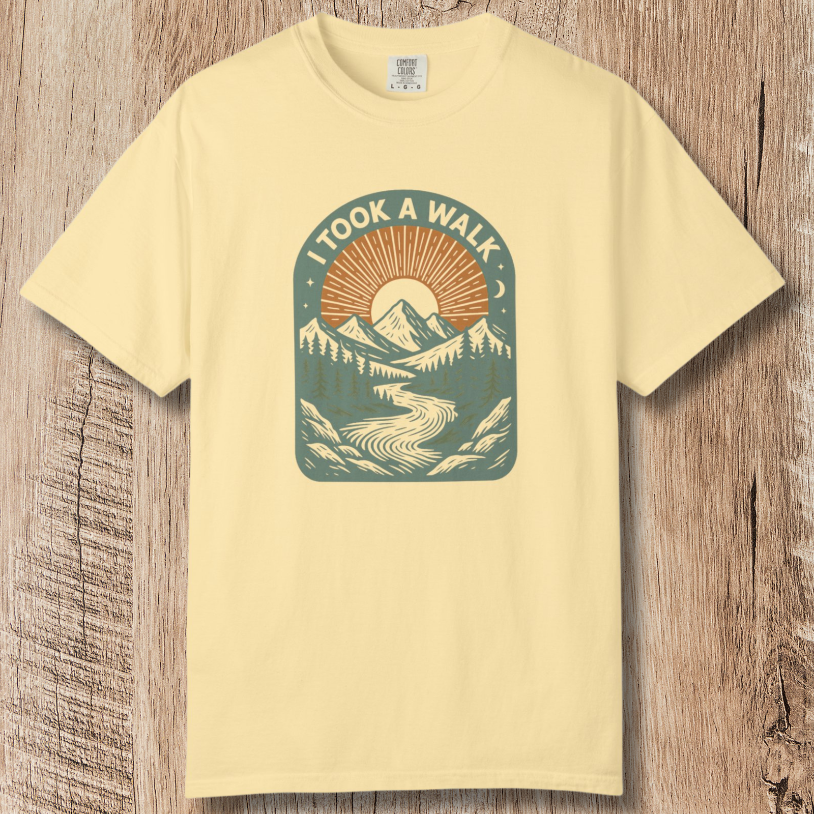 Retro mountain sunrise and river illustration on nature graphic yellow t-shirt wit 'I TOOK A WALK' text.