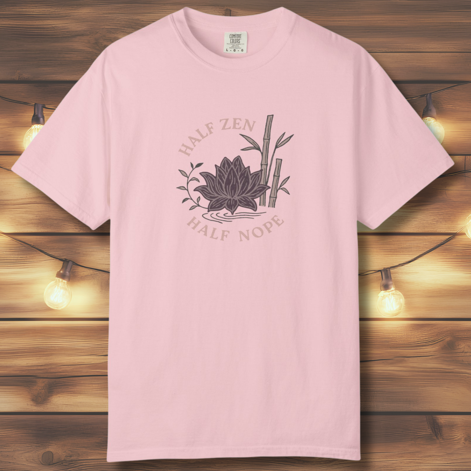 Blossom Comfort Colors t-shirt with hand-drawn lotus sunburst and “Half Zen Half Nope” text on a wood background