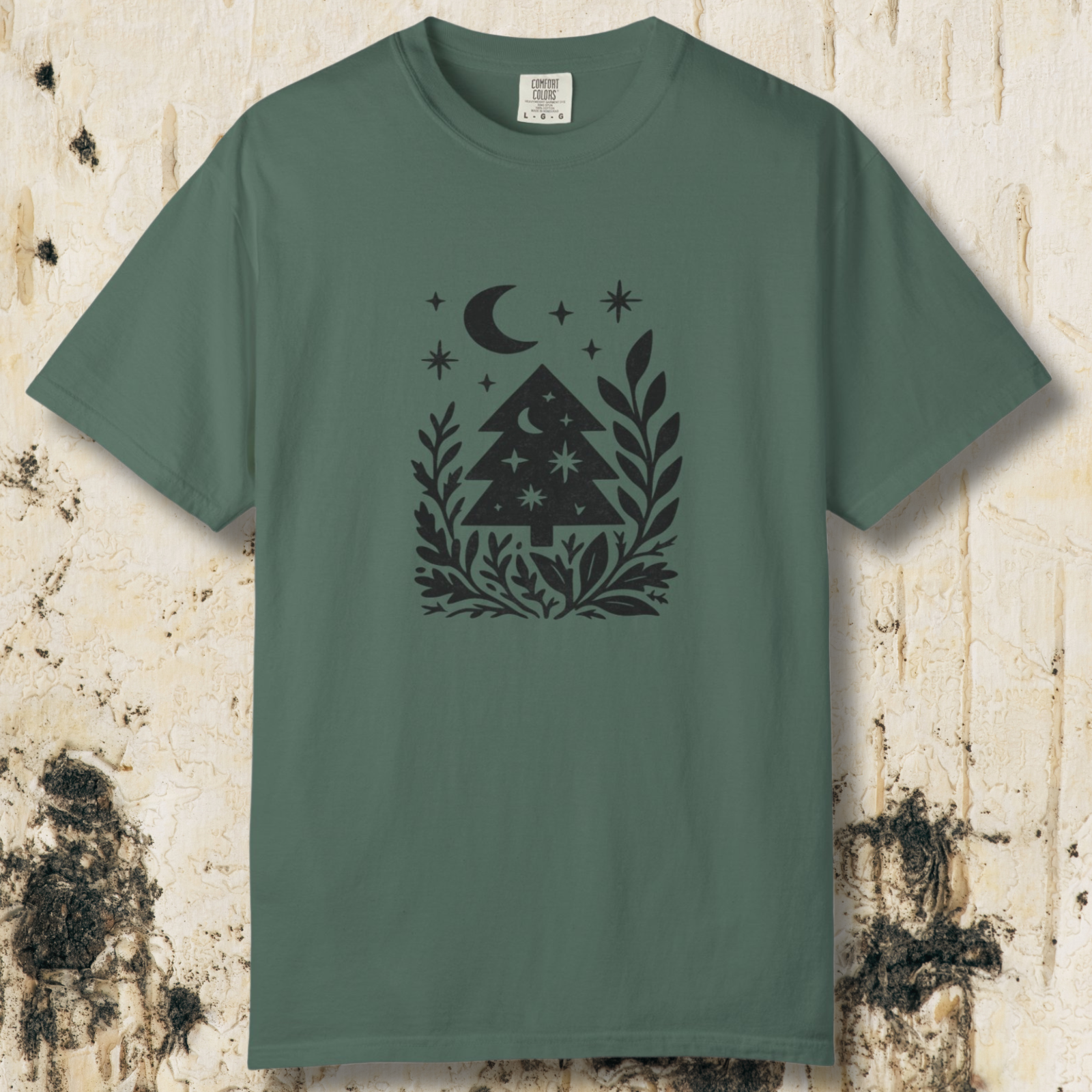 Blue Spruce unisex t-shirt laying flat with charcoal grey pine trees and crescent moon graphic on wood backdrop.
