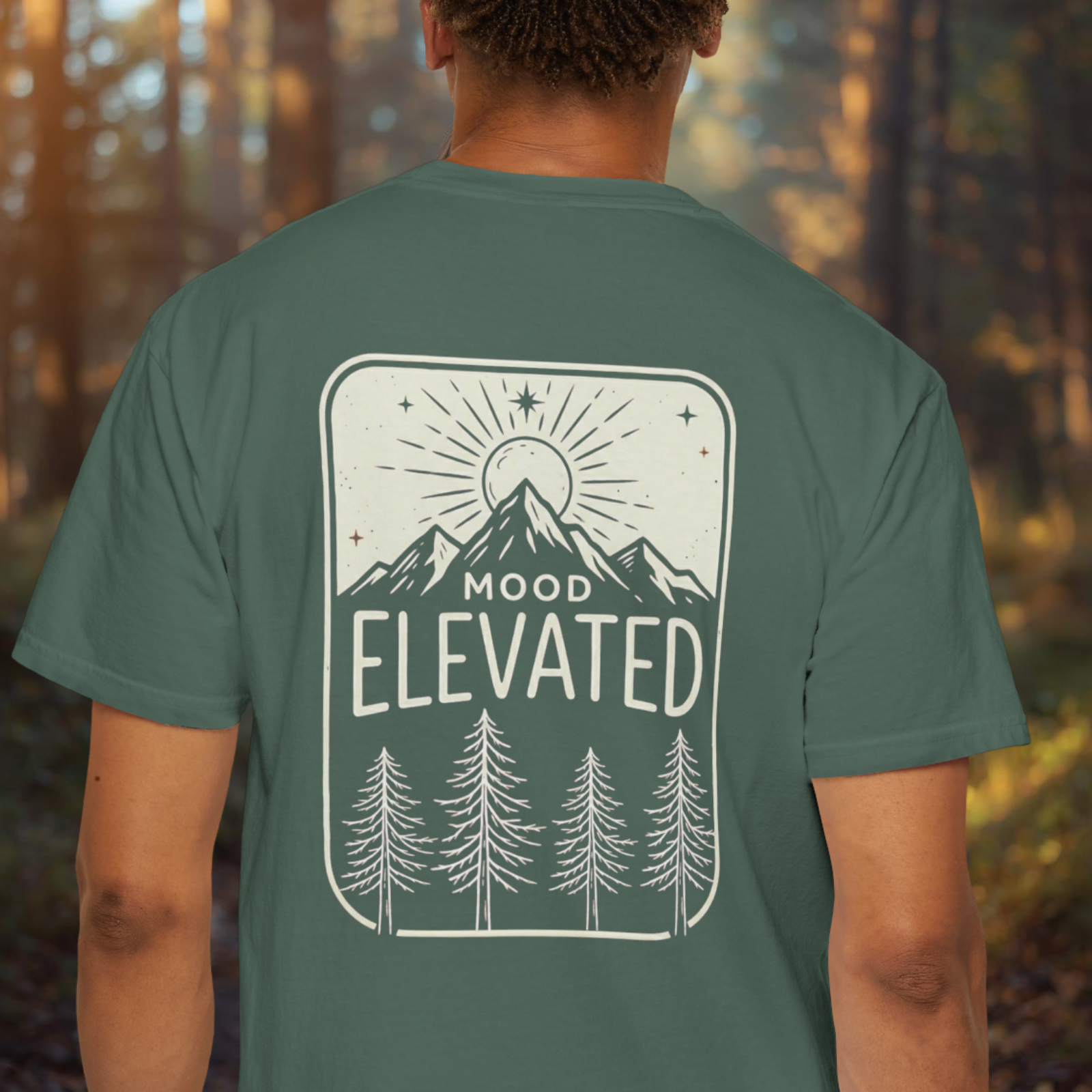 Model wearing Mood Elevated tee showing back print mountain sunrise design.