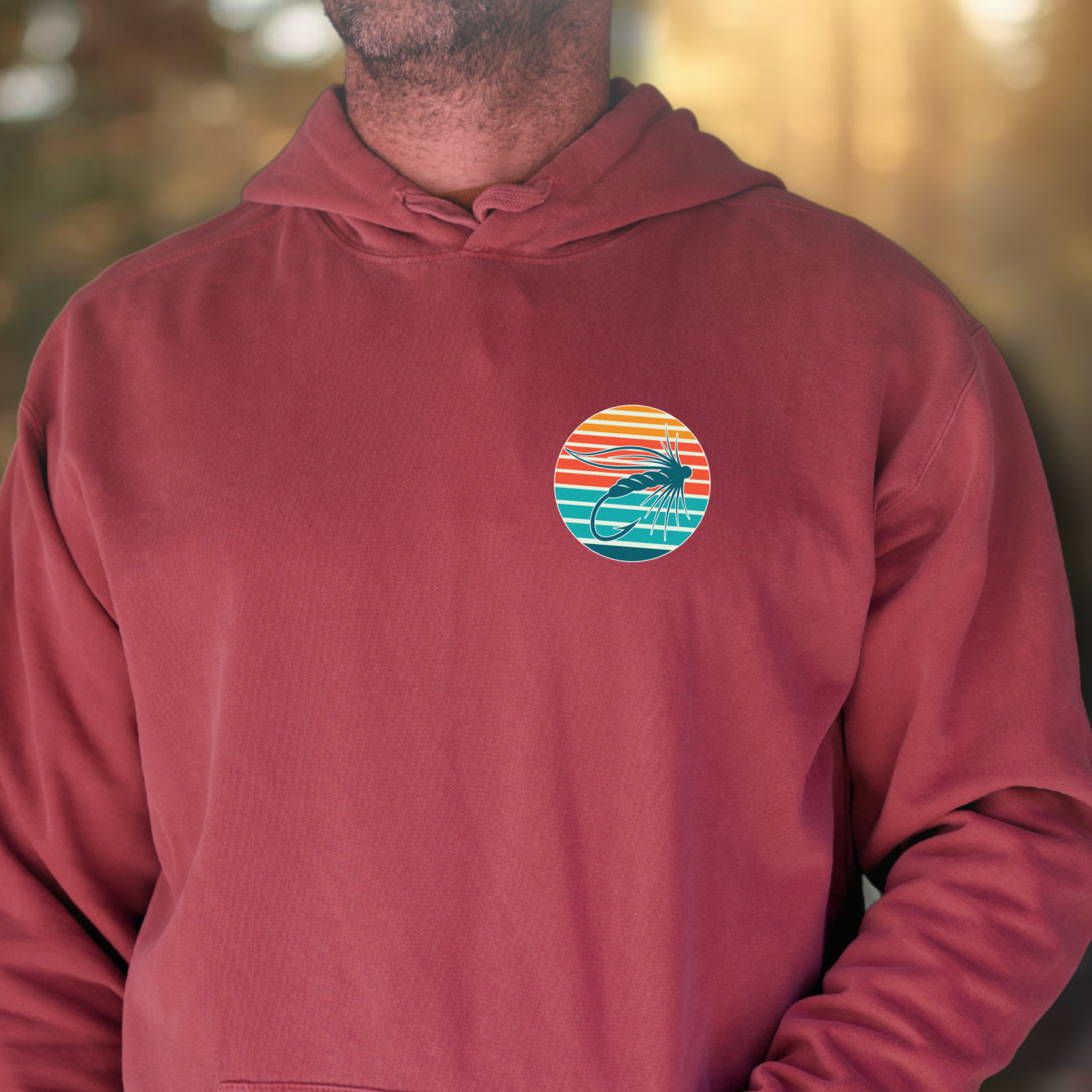 Front view of maroon hoodie with a small left-chest round badge detail (fly fishing themed).