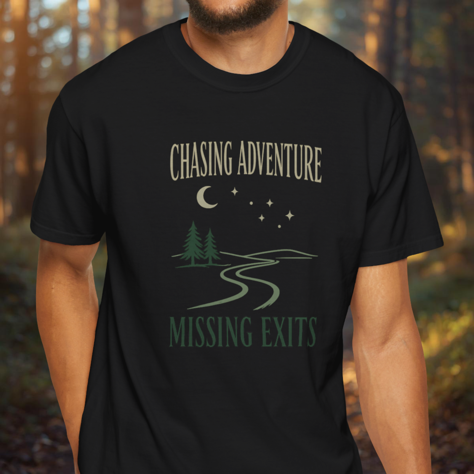 Black t-shirt with 'Chasing Adventure Missing Exits' design worn by a person in a forest setting