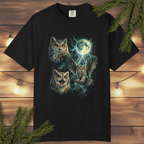 Black t-shirt with owl design on a wooden surface with lights and branches.