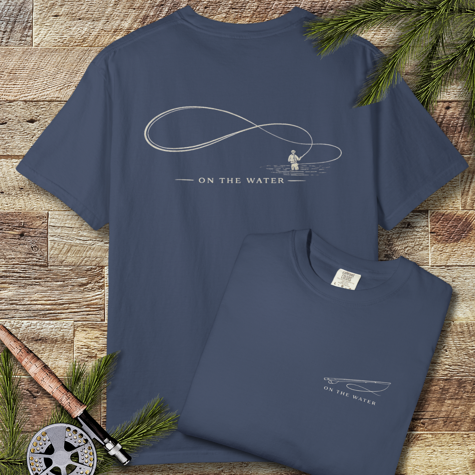 Back and folded front of midnight-colored Comfort Colors t-shirt with minimalist fly fishing line art and “On The Water" text