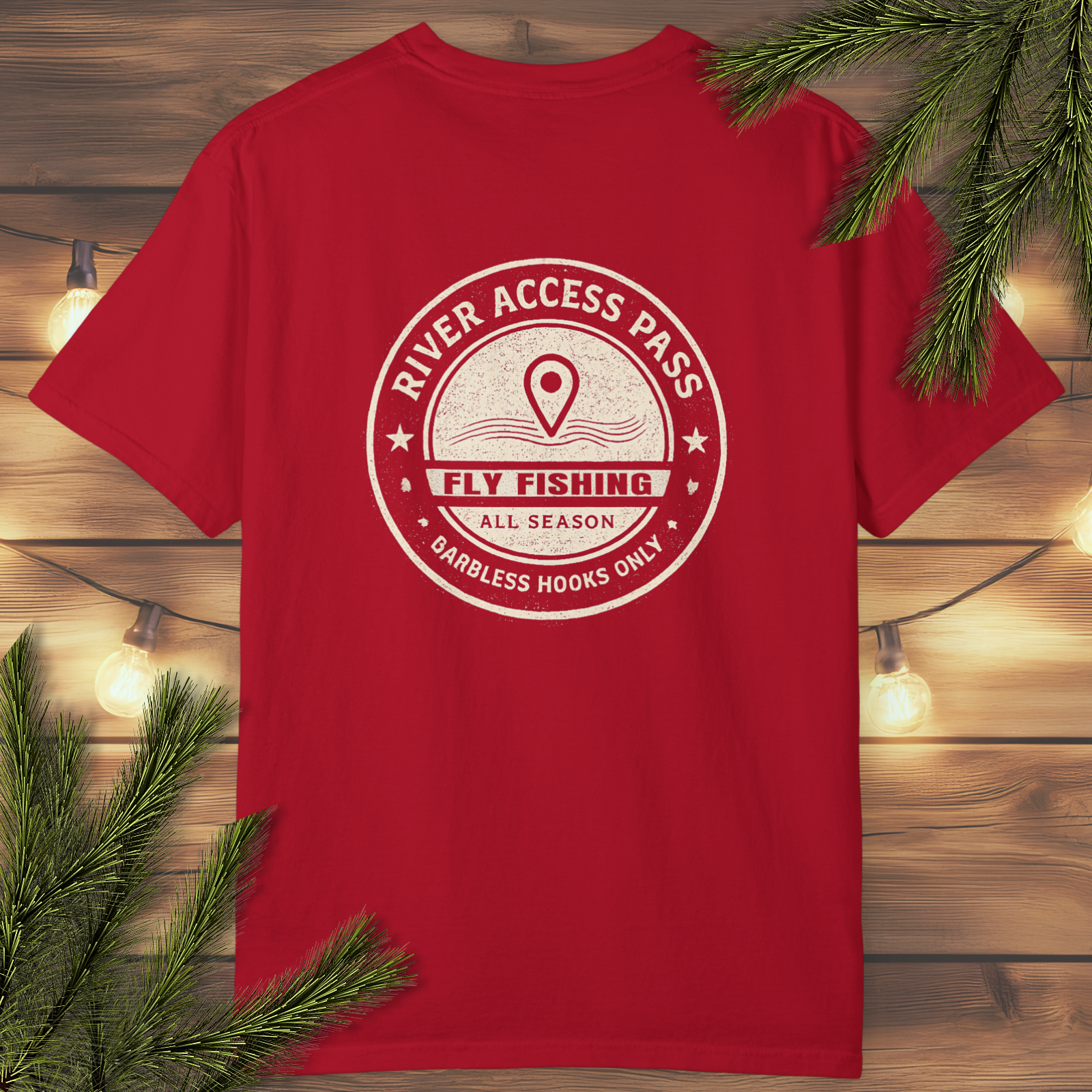 Red t-shirt with River Access Pass fly fishing vintage badge graphic on a wooden background with greenery