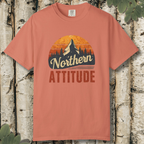 Terracotta unisex t-shirt with “Northern Attitude” retro mountain sunset graphic laid flat on a wooden background.