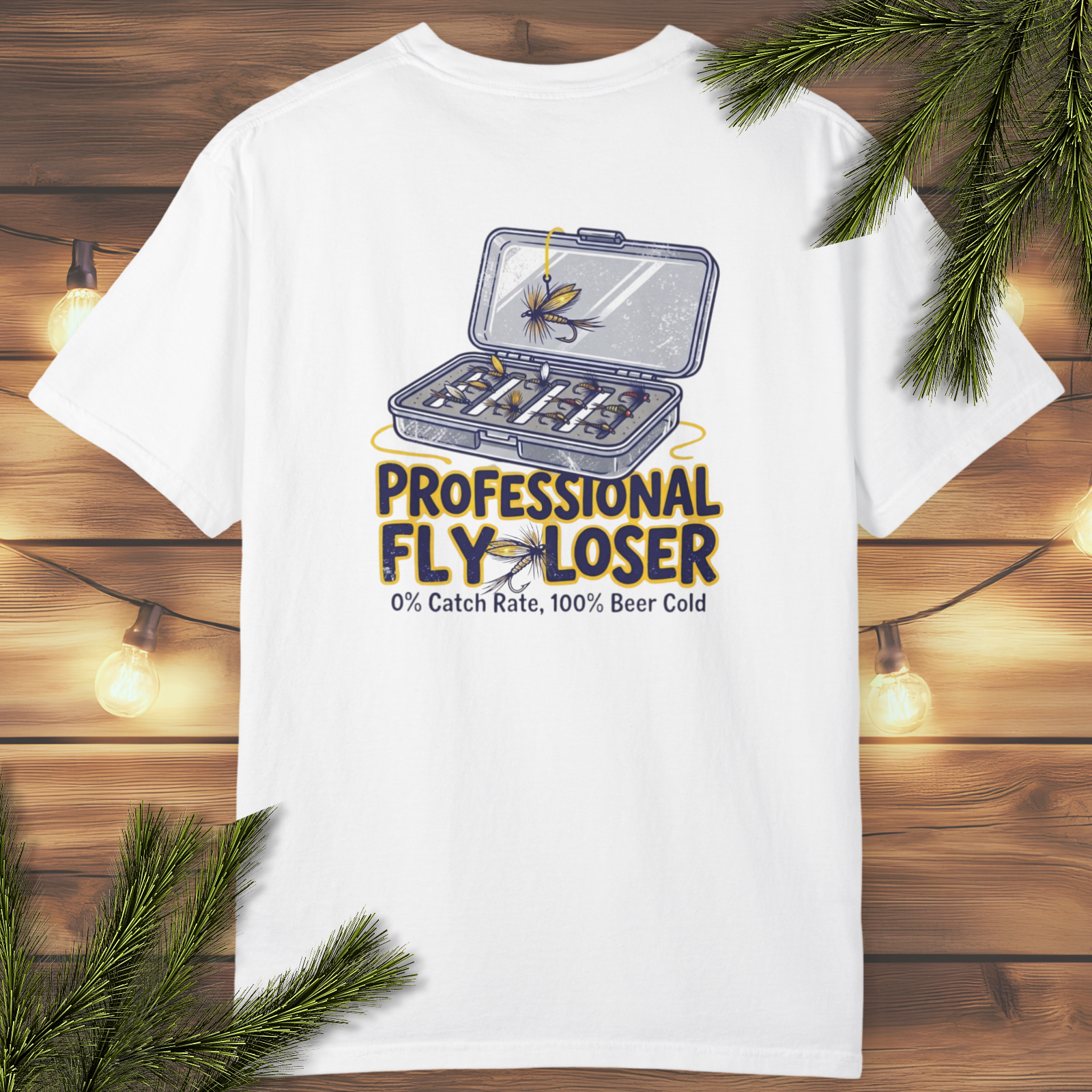 White t-shirt with a fly fishing-themed graphic and text on a wooden background with lights and greenery.