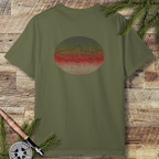 Hemp green t-shirt with retro “trout bum” rainbow trout illustration on the back, styled flat on rustic wood with fly-fishing rod and evergreen branches