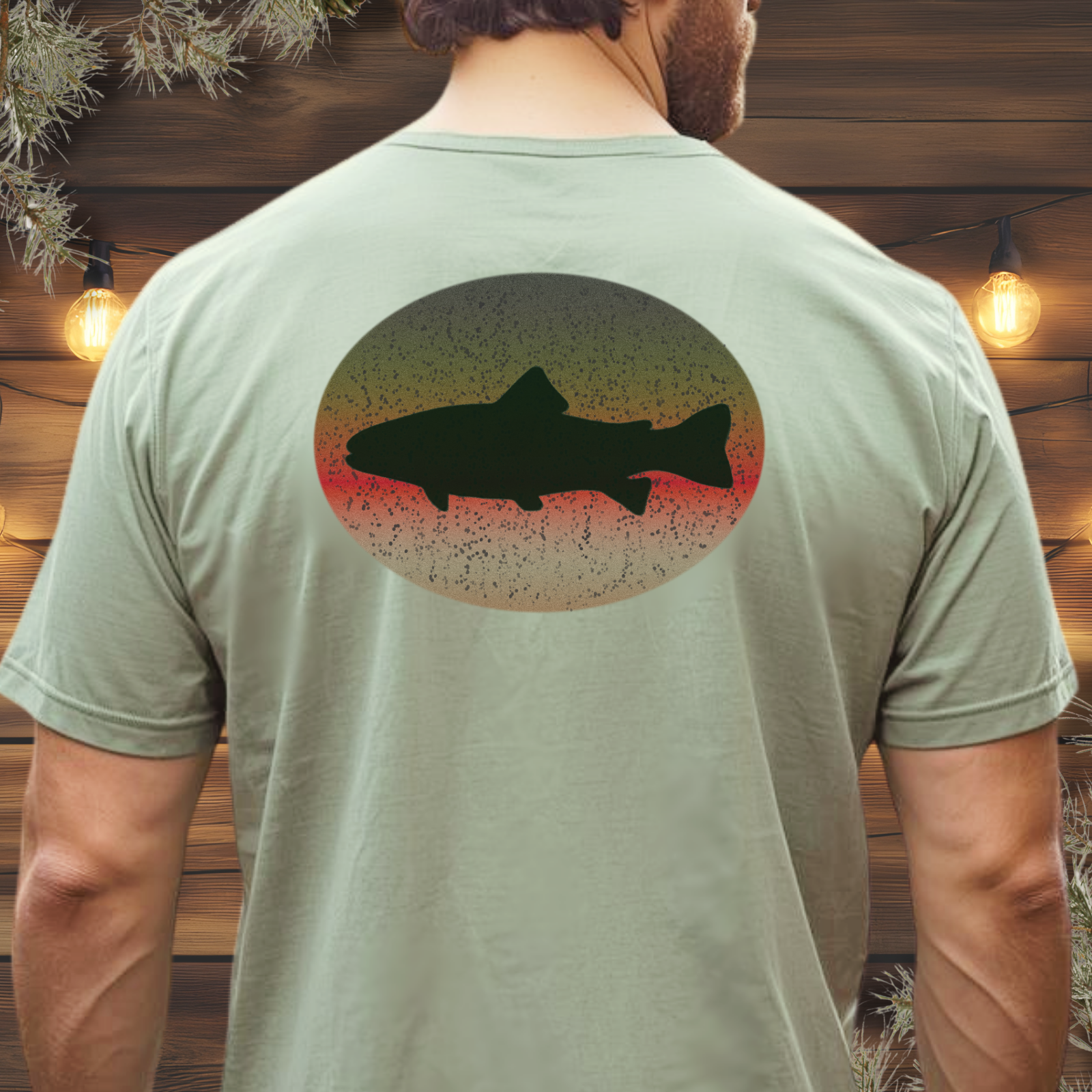 Person wearing a green t-shirt with a fish design on the back, standing against a wooden wall.