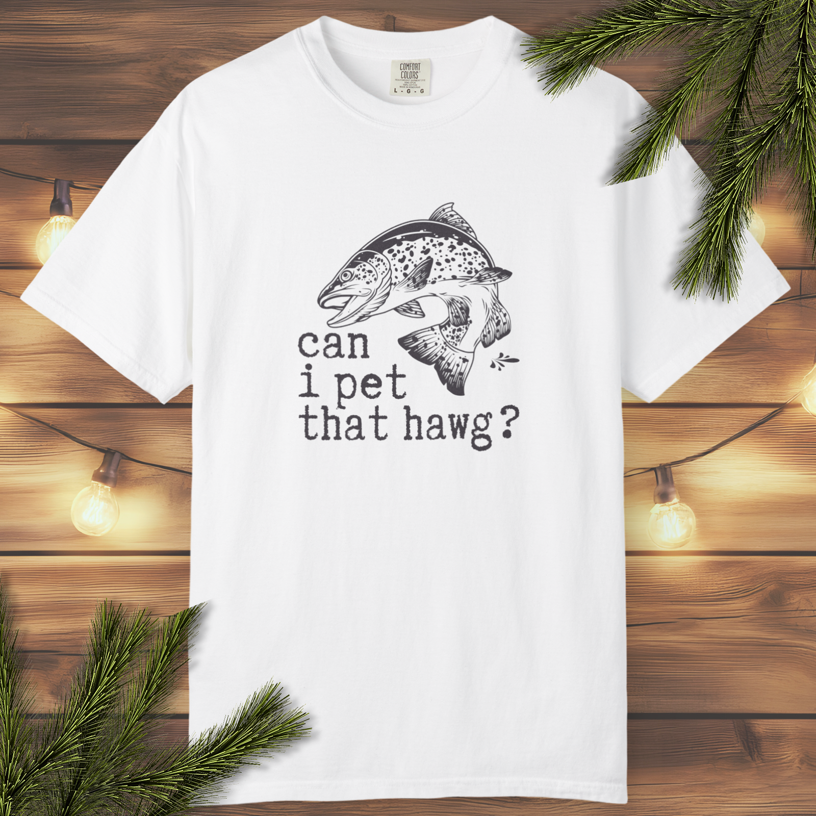 White t-shirt with fish graphic and text on a wooden background