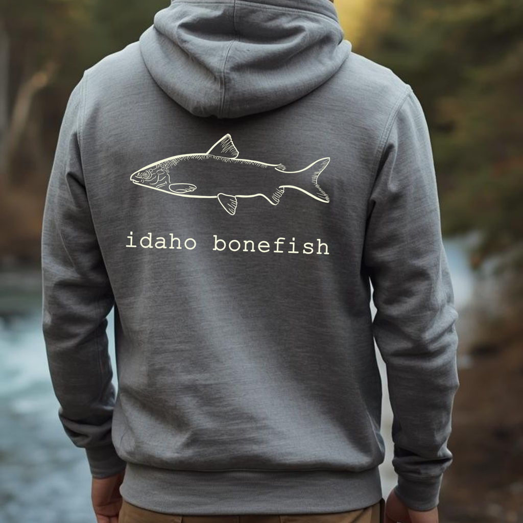 Person wearing a gray hoodie with 'idaho bonefish' design outdoors.